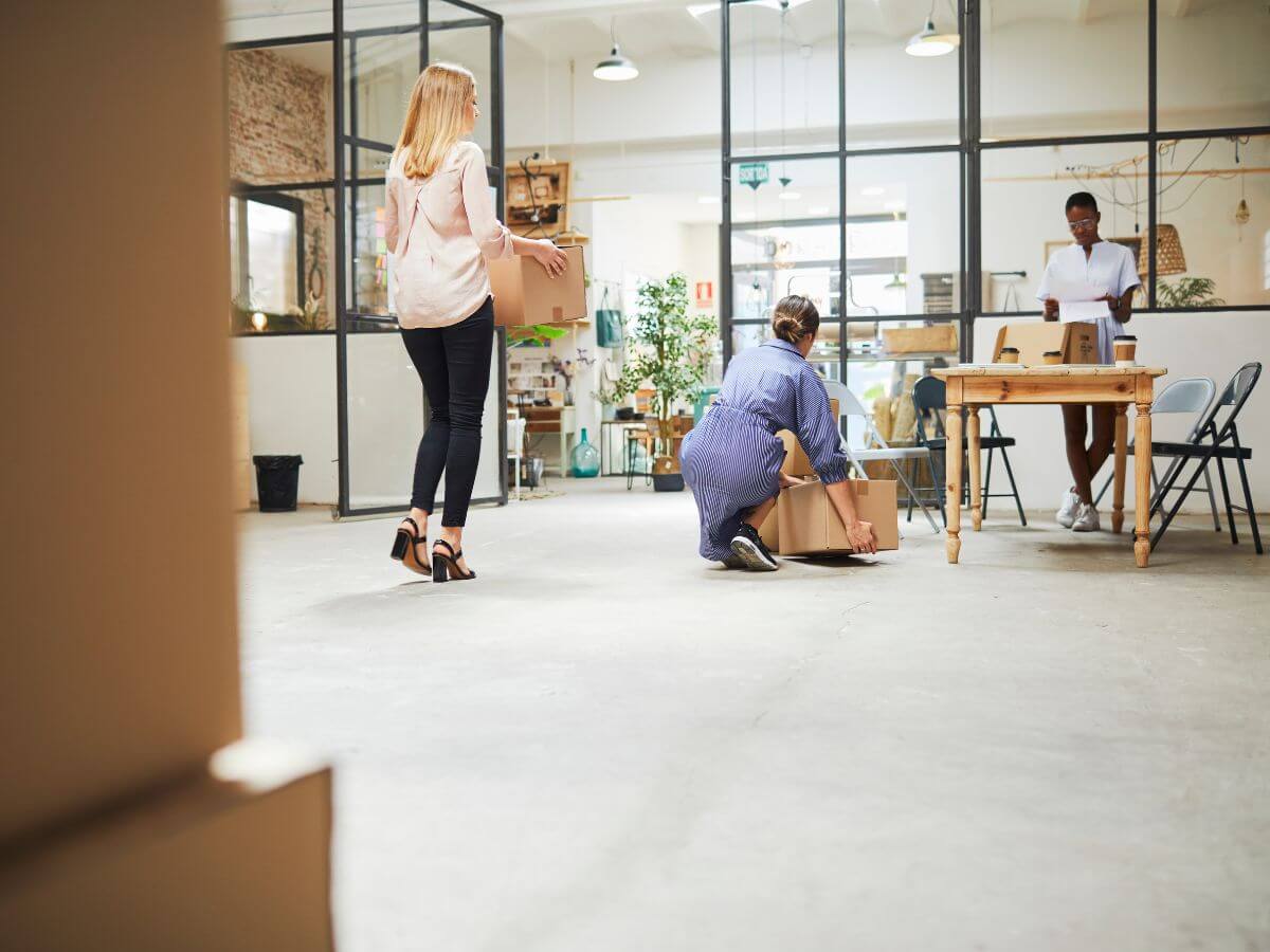 Women carrying moving boxes to their new office space